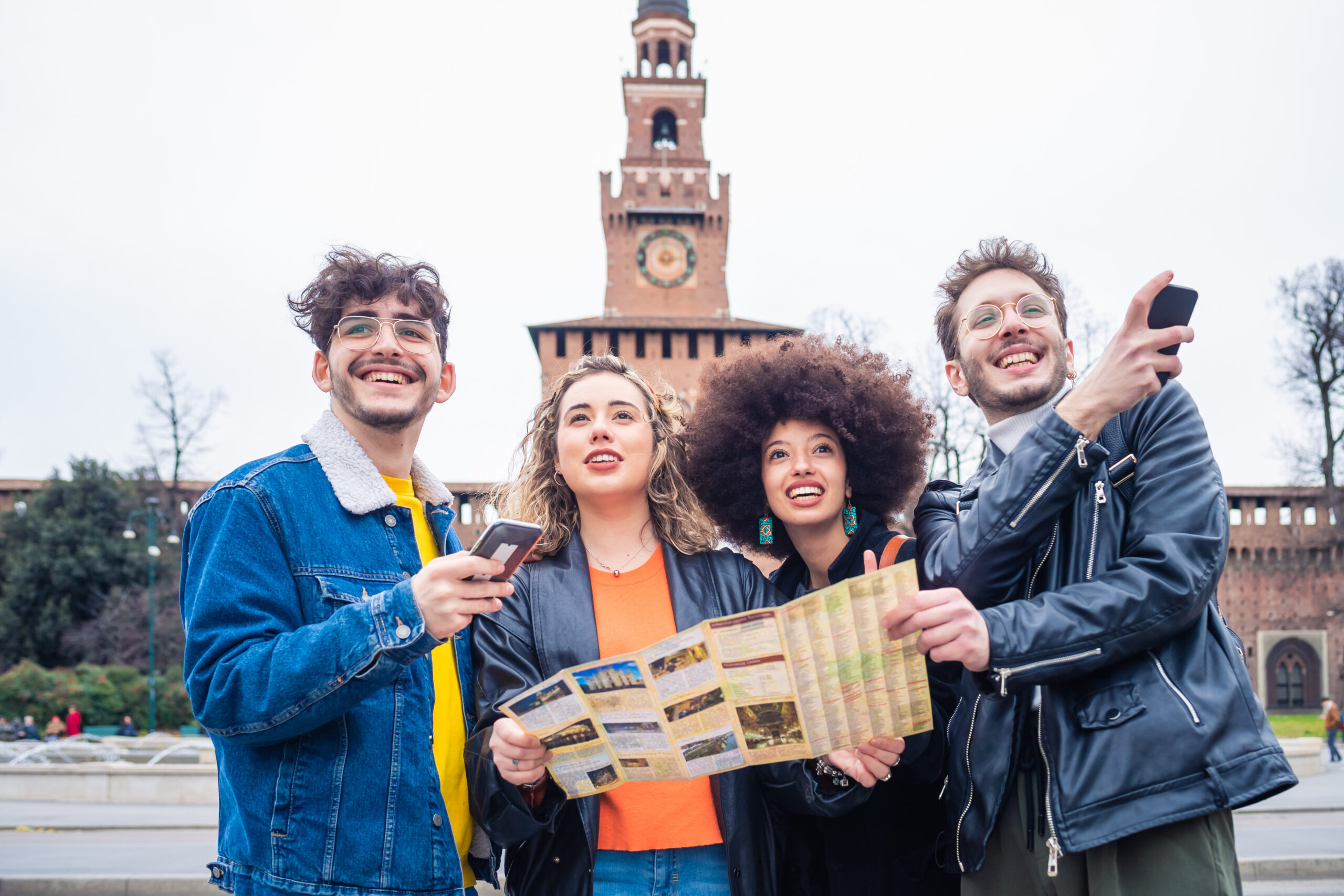 Group of young beautiful multiethnic friends tourist outdoor using map - tourism, traveller, exploration concept